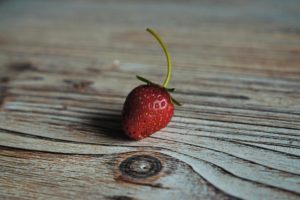little red strawberry on brown wood table ALT TEXT: Tag: cognitive behavioral self-care strategies