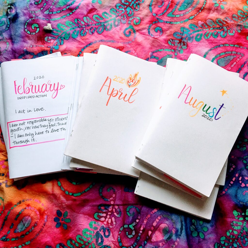 stacks of journals on a multi-colored pink, orange, blue, green cloth with February, April, August titles showing tag: dear 2020